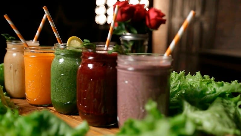 A row of colourful juices in glass jars with striped straws