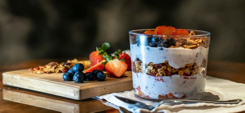 A small glass of yoghurt parfait topped with strawberries and blueberries