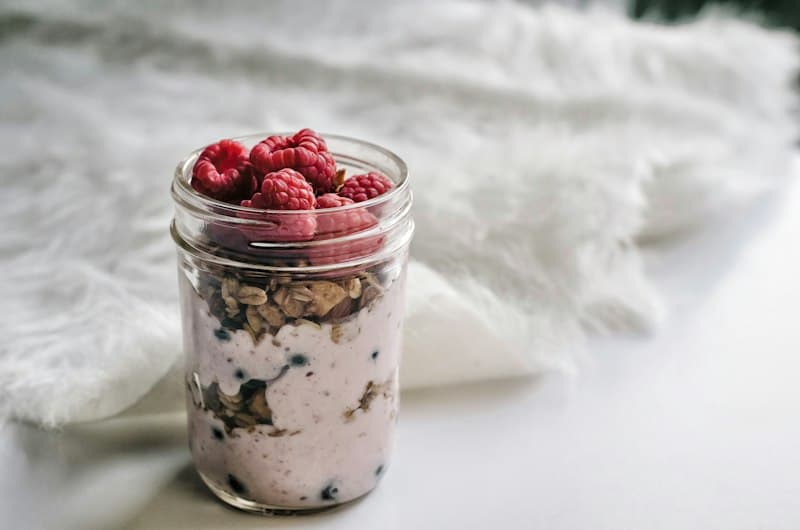 A small jar of oats and yoghurt topped with fresh raspberries